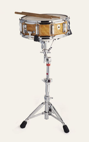 Foto de uma caixa, um instrumento de percussão de formato retangular, com uma pele esticada em uma extremidade. Geralmente feita de madeira, metal ou plástico, a caixa é tocada batendo na pele com baquetas ou com as mãos.